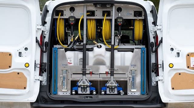 A service van's cargo bay fitted out with oil change equipment, jacks and an oil tank